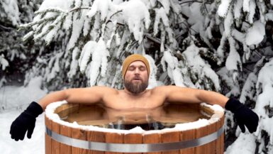 Ein Mann in einer Eistonne vor einer verschneiten Tanne.